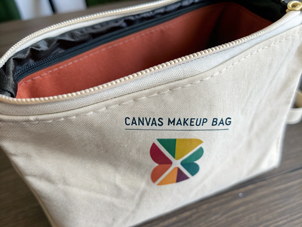 A close-up of a durable, well-made canvas makeup bag with a screen-printed logo