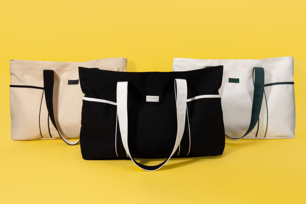 Cotton tote bags in black, beige, and white with contrast handles, designed for everyday carry and sustainable retail packaging.