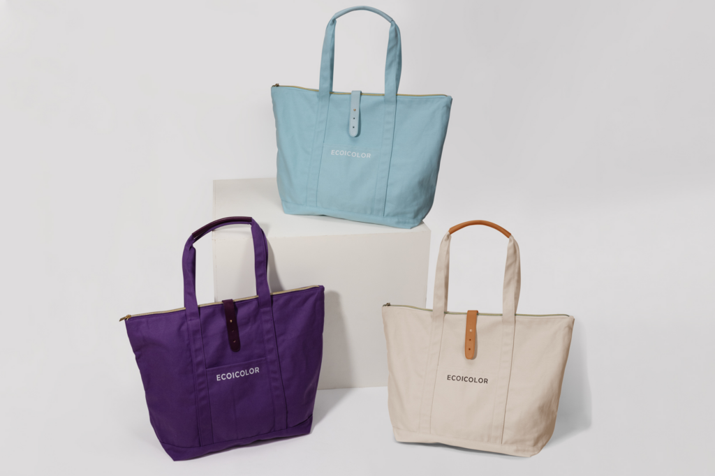 Organic cotton tote bags in pastel blue, purple, and natural beige, designed for sustainable everyday use.