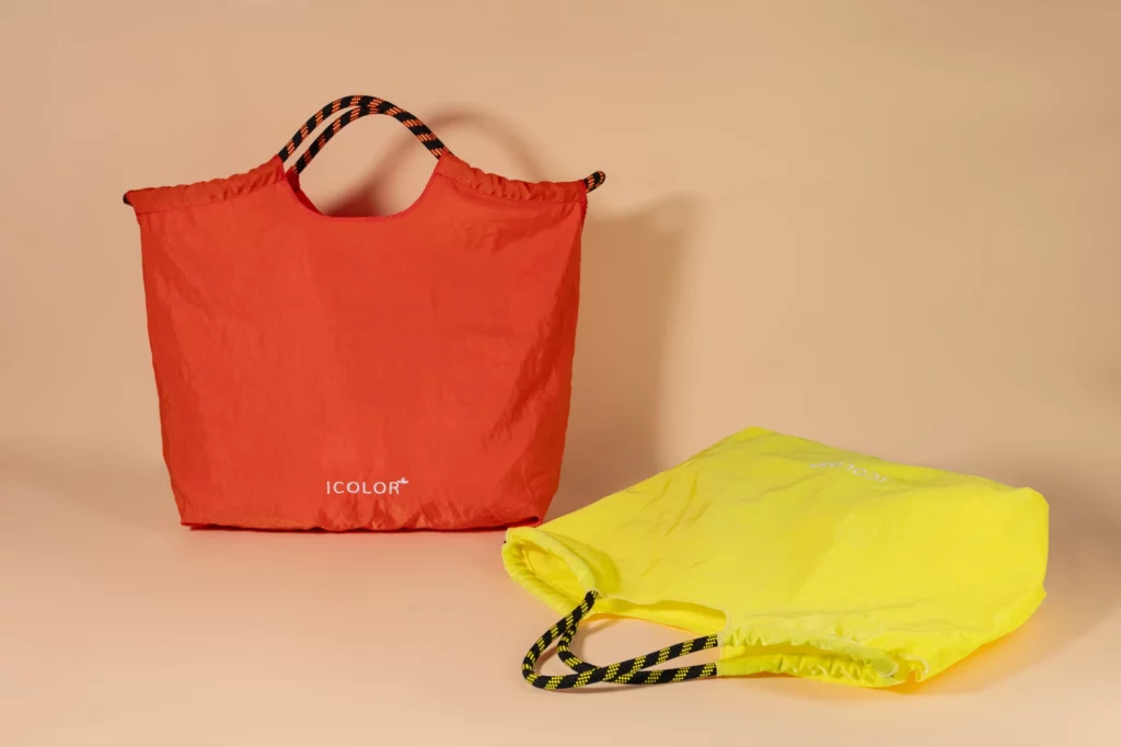 Recycled nylon tote bags in bright orange and yellow, featuring lightweight construction and durable rope handles for eco-friendly everyday use.
